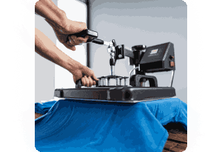 A person using a heat press machine to apply a transfer onto a blue fabric garment on a table.